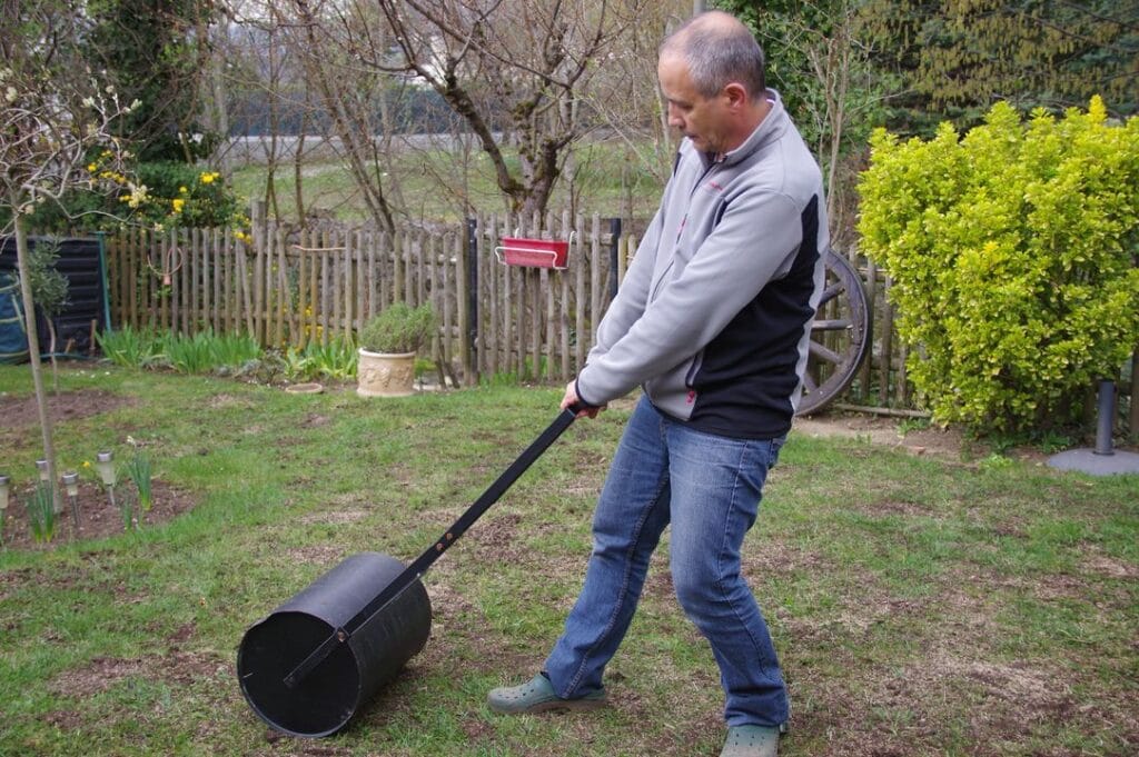 homme passe rouleau pour tasser la terre