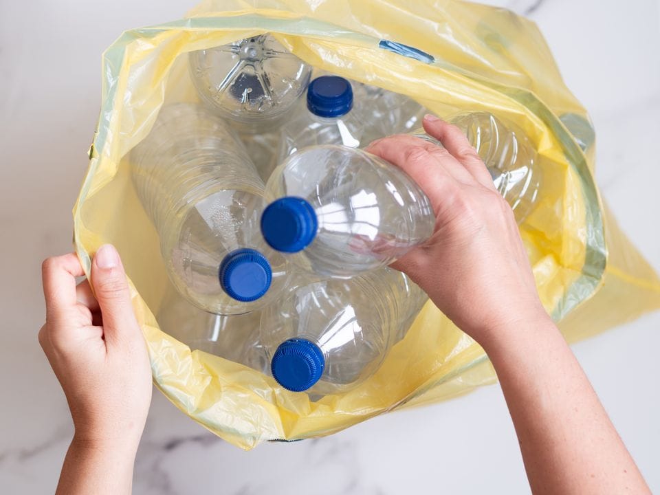 bouteille en plastique a recyclées Femme mettant des bouteilles en plastique usagées dans un sac à ordures